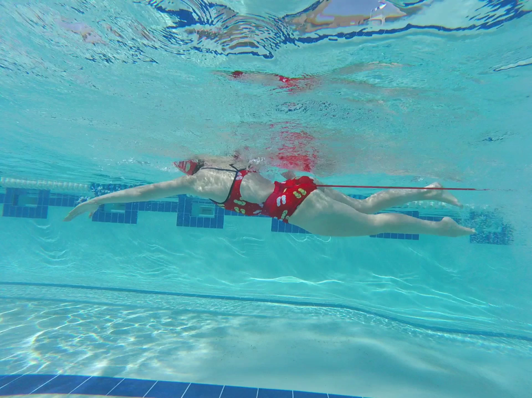 A swimmer training in the pool with a power cord to improve resistance training